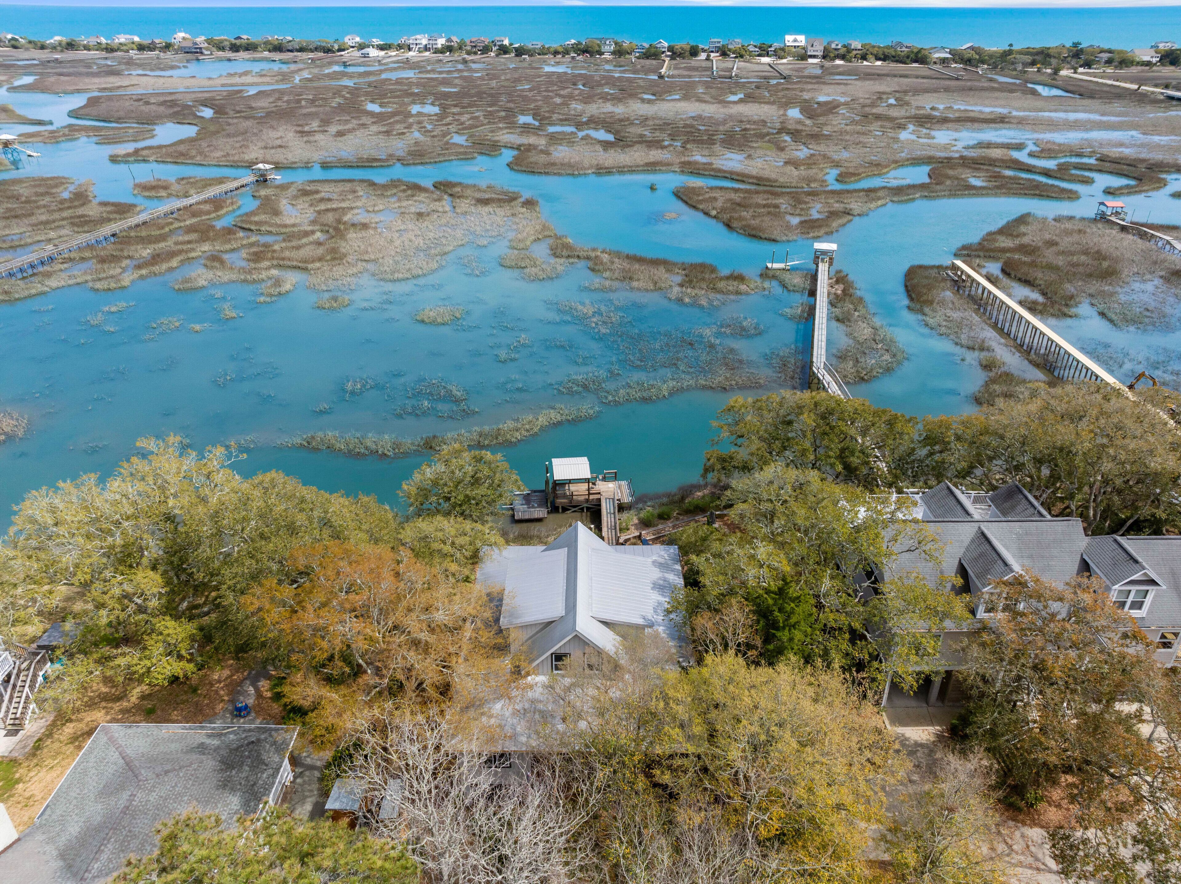 Zona costera con un muelle que se adentra en una laguna, rodeada de edificios residenciales y abundante vegetación.