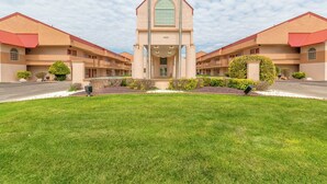 A hotel with a central tower, symmetrical wings, and a well-maintained lawn. - HomeTowne Studios by Red Roof Amarillo West (Amarillo)