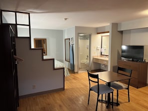 Un appartement moderne comprenant un coin repas, une cuisine et une salle de bain avec douche.