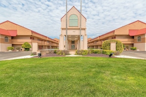 A hotel with a central tower, symmetrical wings, and a well-maintained lawn.