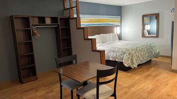 Een slaapkamer met een bed, bureau, stoel, kast en een schilderij aan de muur.