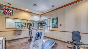 Ein Fitnessraum mit Laufbändern, einem Ergometer und einer Spiegelwand.