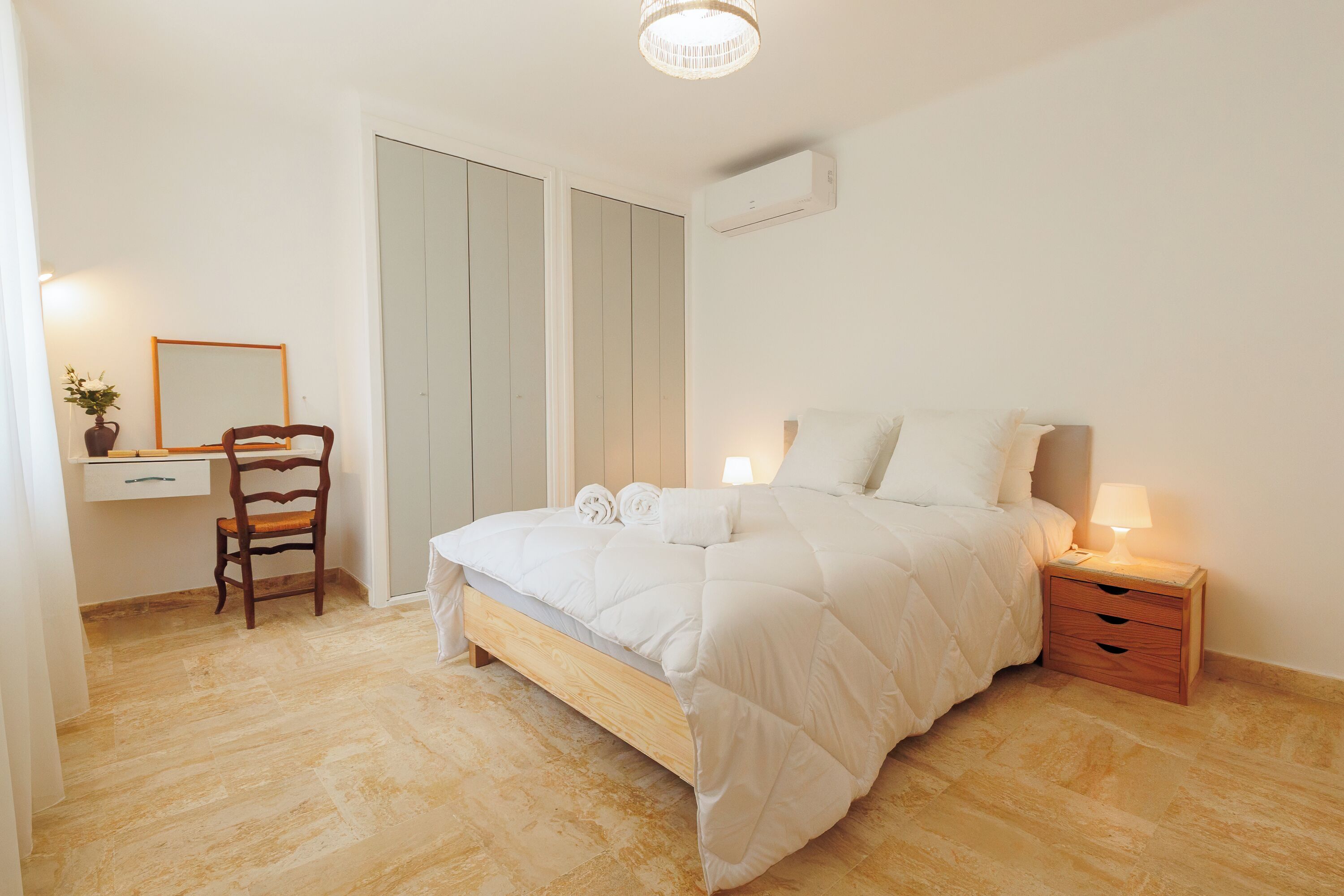 Une chambre à coucher comprenant un lit, une table de chevet, une chaise et un bureau avec une autre chaise.