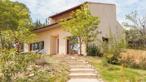 A modern house with a stone staircase leading to a red door, surrounded by greenery. - Grande Maison Familiale Avec Piscine Dans Quartier Résidentiel Calme (Langlade)