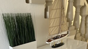 Un mostrador de recepción blanco con un modelo de velero y una maceta con plantas verdes.