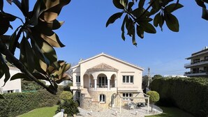 Una casa de dos pisos con piscina, rodeada por un césped cuidado y setos.