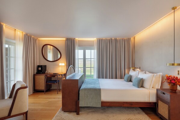 A hotel room with a bed, a desk, a chair, a mirror, and a window with curtains. - Quinta Do Paral (Vidigueira)