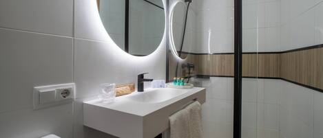 A modern bathroom with a white sink, a mirror, a towel, and a shower.