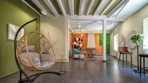A spacious room with a hanging chair, a sofa, and a dining area with stools.