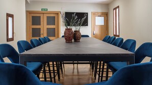 A conference room with a long table, blue chairs, and two decorative vases.