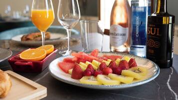 A breakfast setting with a plate of fruit, a glass of orange juice, and bottles of alcohol.