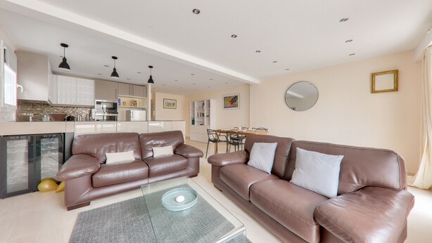 A modern living room with a brown leather sofa, a glass coffee table, and a kitchen in the background. - Flat for 4 in the centre of Sarzeau (Sarzeau)