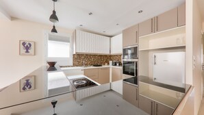 A modern kitchen with a central island, stainless steel appliances, and a backsplash with a mosaic tile pattern. - Flat for 4 in the centre of Sarzeau (Sarzeau)