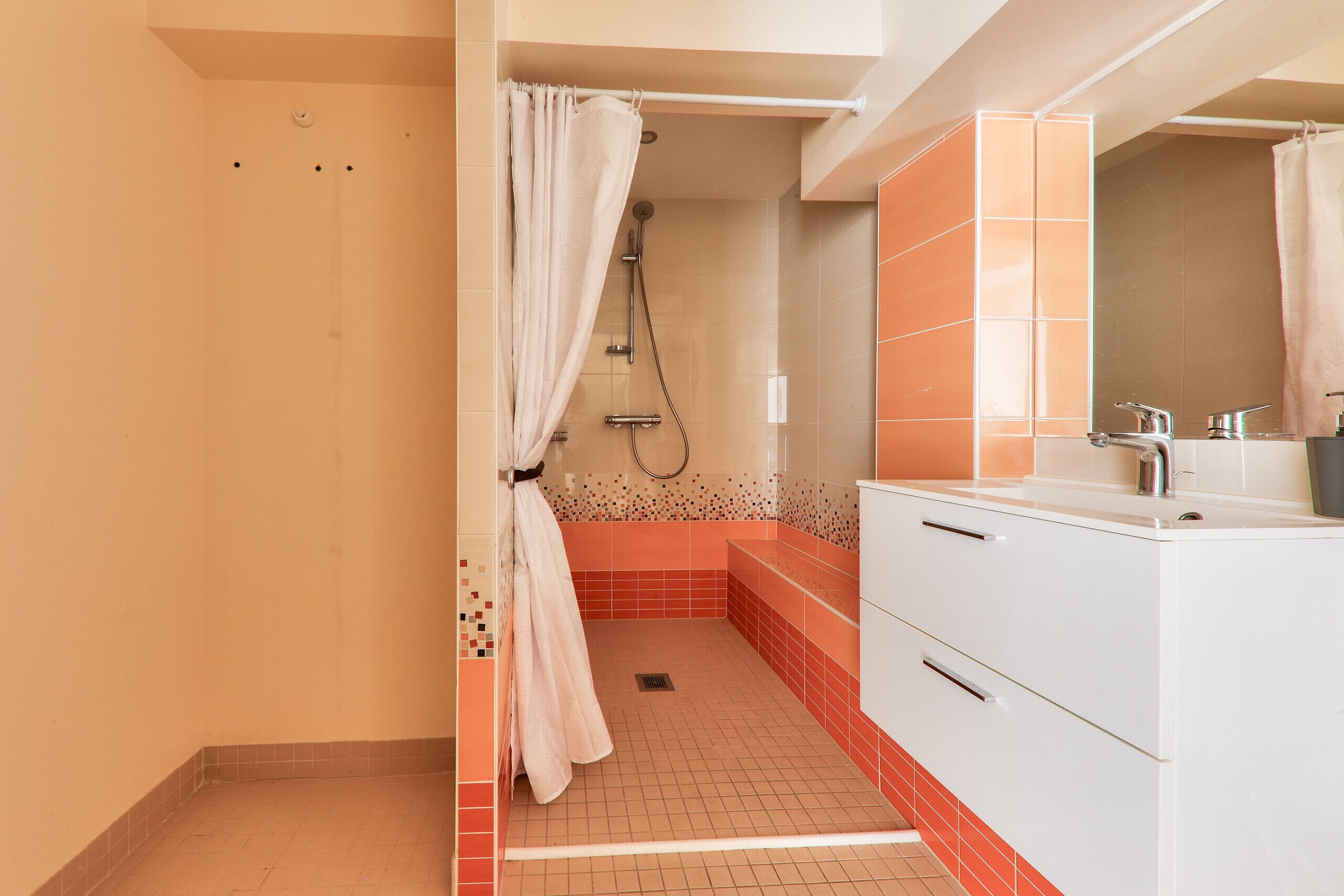 A bathroom with a shower, a sink, and a mirror.