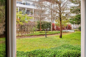 Stroll through our serene courtyard, surrounded by lush trees and shrubs, along a paved walkway.