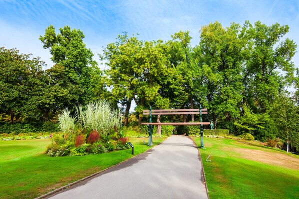 Stroll through the lush garden, lined with trees and shrubs, and pause at the inviting wooden bench.