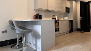 Et moderne køkken med en central ø, barstole og indbyggede apparater.