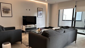 En moderne stue med et stort fladskærms-tv, en grå sofa og et sofabord.