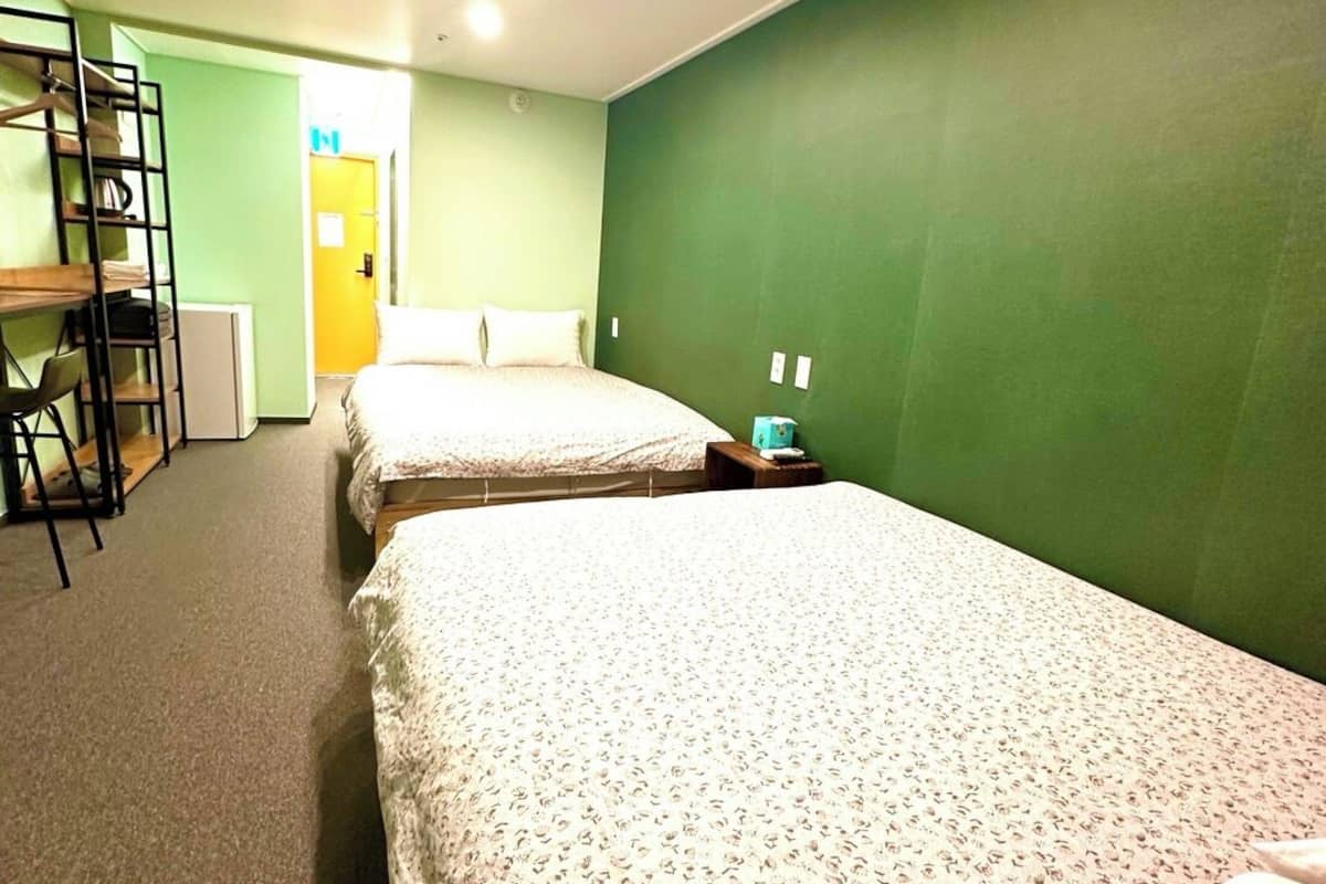 A hotel room with two beds, a desk, and a chair.