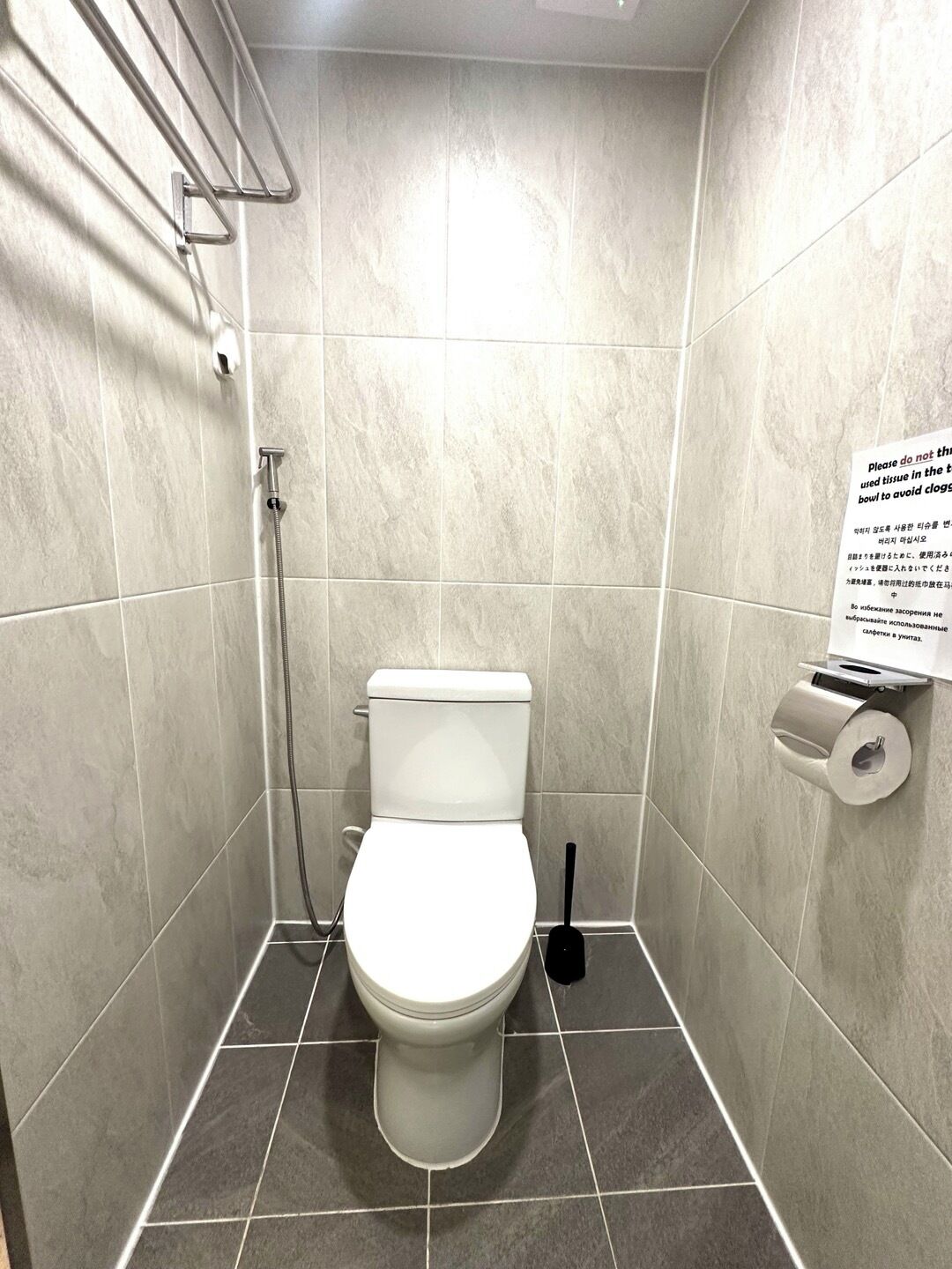 Pieni, moderni kylpyhuone, jossa on wc, käsienkuivaaja ja paperipyyheannostelija.