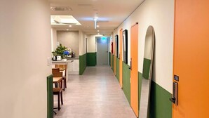 A hotel corridor with a dining area on the left, featuring a table and chairs. - R Guesthouse Jongmyo (Seoul)