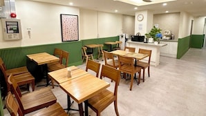 A restaurant with wooden tables and chairs, a counter with a cash register, and a ceiling fan. - R Guesthouse Jongmyo (Seoul)