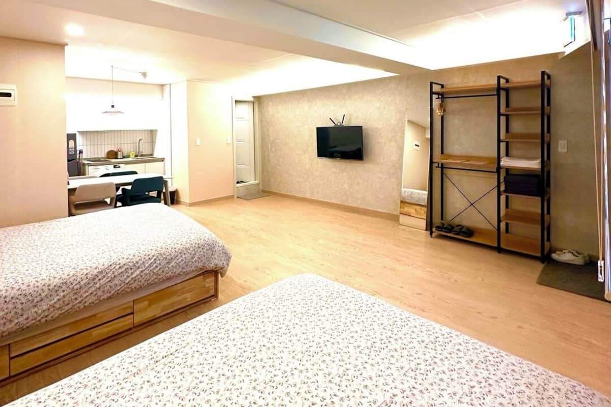 A spacious room with two beds, a TV mounted on the wall, and a built-in shelf unit.