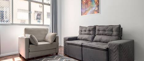 A living room with a beige sofa, a grey sofa, and a patterned rug.