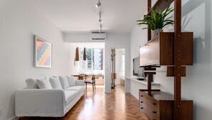 A modern living room with a white sofa, wooden flooring, and a built-in TV shelf. - 5 Minutes From the Beach and a View of Christ Br904 (Rio de Janeiro)
