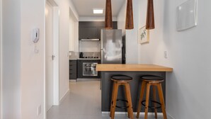 A modern kitchen with a central island, two bar stools, pendant lights, and a refrigerator. - 5 Minutes From the Beach and a View of Christ Br904 (Rio de Janeiro)