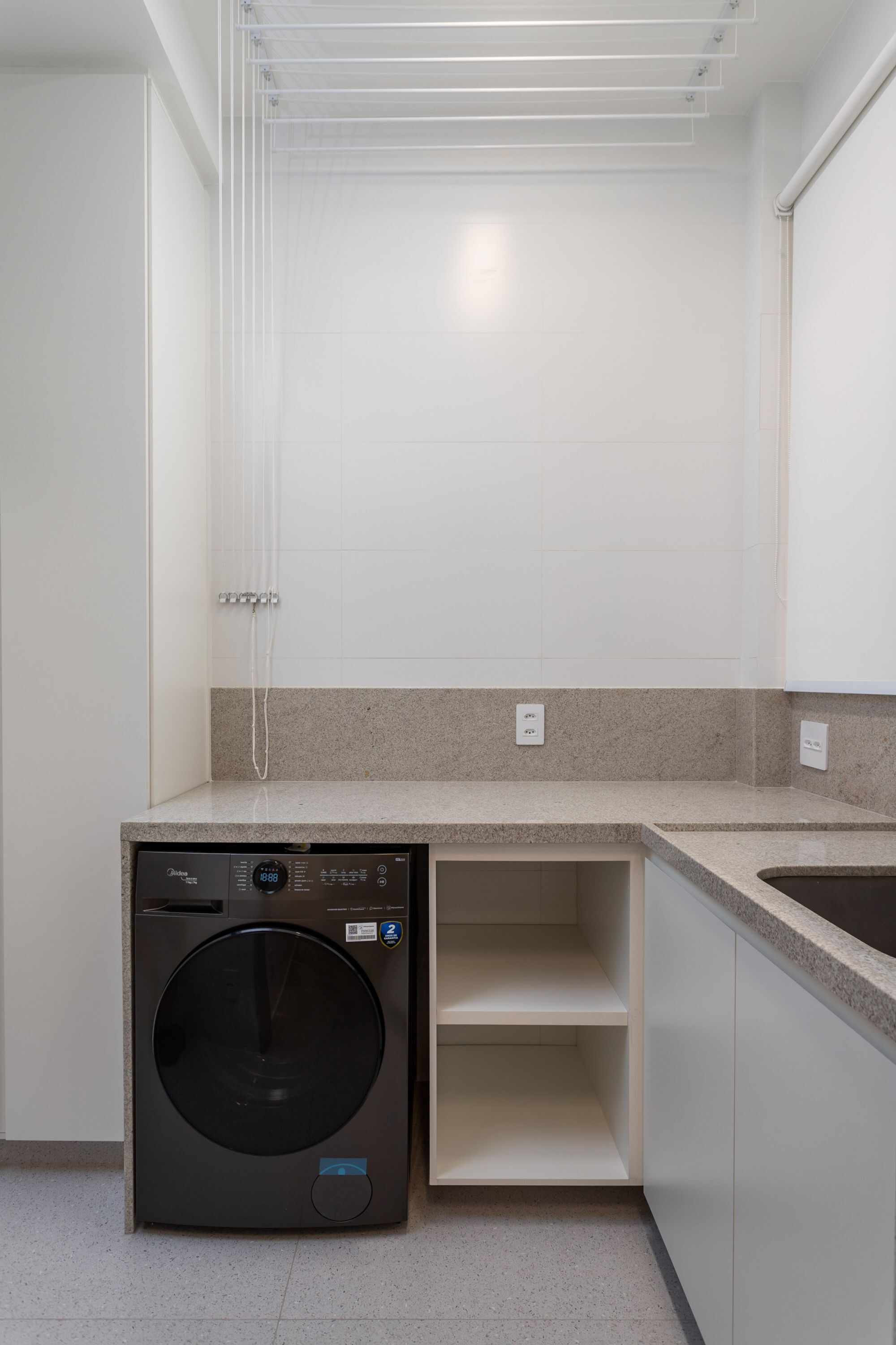 Een kleine keuken met een ingebouwde wasmachine en droger, een aanrecht en een spoelbak.