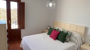 Un dormitorio con cama, mesita de noche, cómoda y lámpara colgante.
