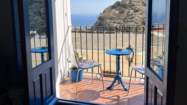 Un balcón con vista al mar, una mesa y dos sillas.
