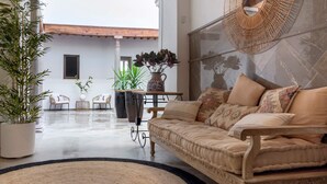 Ein modernes Wohnzimmer mit einem beigefarbenen Sofa, einem runden Spiegel und Blumentöpfen.