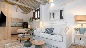Ein modernes Wohnzimmer mit einem weißen Sofa, einem runden Couchtisch und einem Essbereich mit einem Glastisch und Stühlen.