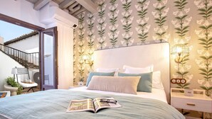 Ein Schlafzimmer mit einem Bett, einem Nachttisch, einer Lampe und einem Fenster.