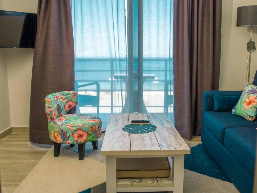 Una habitación con sofá, sillón, mesa y televisor.