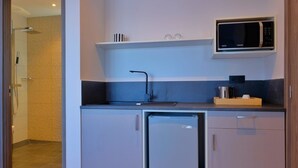 A compact kitchenette with a microwave, a sink, and a small refrigerator. - BLUE VELVET (Nosy Be)