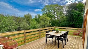 A wooden deck with a table and chairs, surrounded by a wooden fence, overlooking a forested area. - Le Gîte Isabel en Dordogne, Près de Sarlat (Saint-Crépin-et-Carlucet)