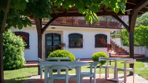 A patio with a table and chairs, a covered area with a pergola, and a building with windows and a staircase. - B&B Hibiscus (Agropoli)