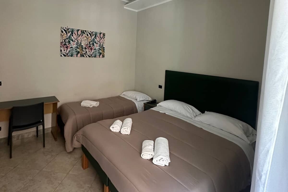A hotel room with two beds, a desk, and a chair.