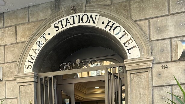 The entrance to the Smart Station Hotel with a clock on the wall and a digital display board. - Smart station hotel  (Naples)
