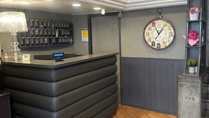 A reception area with a counter, a clock, and a wall-mounted key rack. - Smart station hotel  (Naples)