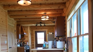 L’intérieur d’un chalet en bois comprend un coin cuisine, un plancher en bois et de grandes fenêtres.