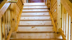 Un escalier en bois, doté d’une rampe, avec, au fond, une commode en bois.