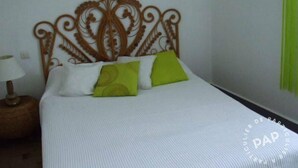 A neatly made bed with a decorative headboard, a bedside lamp, and two pillows.