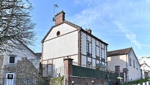 Un edificio tradicional con fachada de piedra, cerca metálica verde y un hidrante rojo.