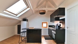 Una cocina moderna con tragaluz, armarios negros y suelo de madera en espiga.