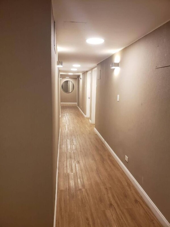 Un pasillo estrecho con suelo de madera y paredes color crema.