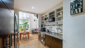 Cocina compacta con lavadora, lavaplatos y comedor con mesa y sillas.
